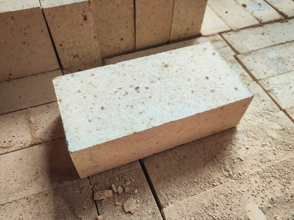 Angled view of refractory firebrick on industrial platform. Heat resistant construction material for furnaces, kilns, and hot industrial processes.